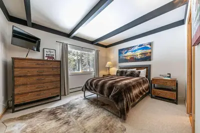 a bedroom with a bed and a dresser and a television at Lakewalk Lodge at the West Shore by Tahoe Getaways, Pet-Friendly w Sauna! in Homewood