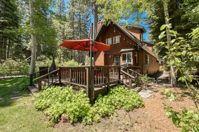 a wooden house with an umbrella in front of it at Lakewalk Lodge at the West Shore by Tahoe Getaways, Pet-Friendly w Sauna! in Homewood