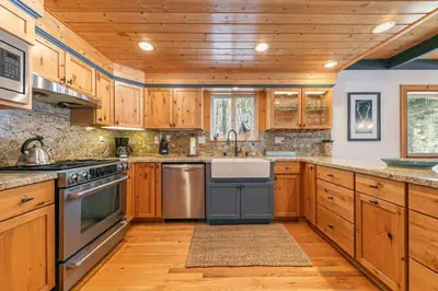 a kitchen with wooden cabinets and stainless steel appliances at Lakewalk Lodge at the West Shore by Tahoe Getaways, Pet-Friendly w Sauna! in Homewood