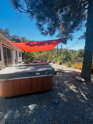 a hot tub sitting outside of a house next to a tree at Fun for 2-Hot Tub-Dogs Ok-Near Bass Lake in Oakhurst