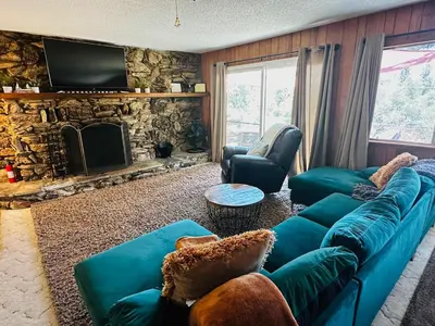 a living room with a blue couch and a stone fireplace at Fun for 2-Hot Tub-Dogs Ok-Near Bass Lake in Oakhurst