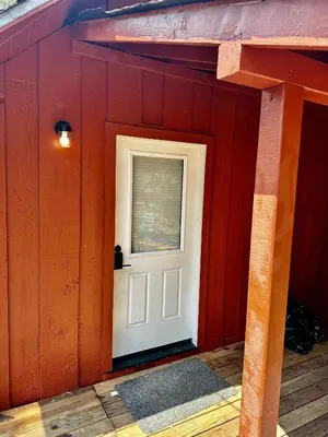 a red building with a white door and a window at The Falls-Overlooks a waterfall-BBQ-Sleeps 4 in Oakhurst
