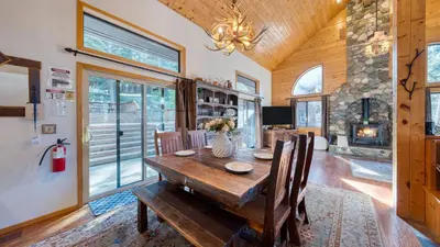 a dining room with a wooden table and a fireplace at Cozy Escape w Hot Tub Deck Access to Tahoe Donner Skiing Alpenglow Chalet by AvantStay in Truckee