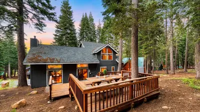a house with a large deck in the woods at Cozy Escape w Hot Tub Deck Access to Tahoe Donner Skiing Alpenglow Chalet by AvantStay in Truckee