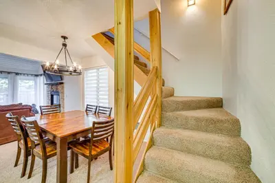a dining room and kitchen with a wooden table and stairs at St Anton Condo in Mammoth Lakes! in Mammoth Lakes