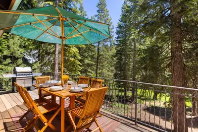 a wooden table with chairs and an umbrella on a deck at Luxury 4BR Retreat Near Northstar Sleeps 10 in Tahoe Vista