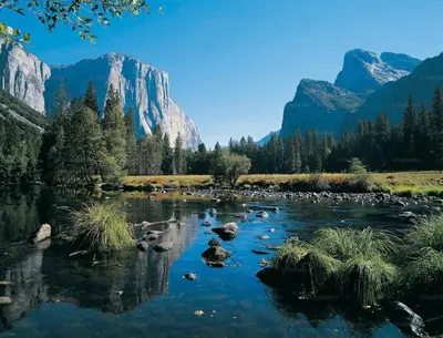 a river with rocks and mountains in the background at The Blue Resort of Yosemite - Pool, Spa, Games in Mariposa