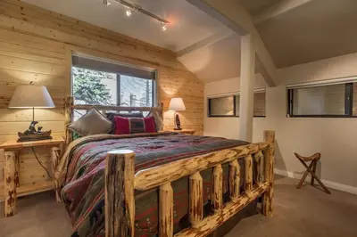 a log cabin bedroom with a large bed and a window at Mammoth Basecamp Condo with Views near Village with AC and Fireplace in Mammoth Lakes