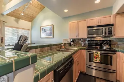 a kitchen with wooden cabinets and a stove top oven at Mammoth Basecamp Condo with Views near Village with AC and Fireplace in Mammoth Lakes