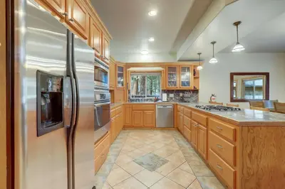 a kitchen with wooden cabinets and a stainless steel refrigerator at TaHaus Hot Tub Pool Table Dog Friendly in South Lake Tahoe