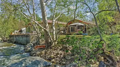 a house next to a river with a house at Riverfront with EV charger - Sequoia River Cottage in Three Rivers