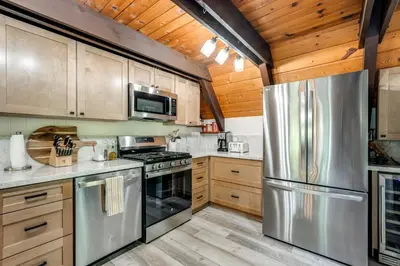 a kitchen with stainless steel appliances and wooden cabinets at Sleek Blue Lake Springs Retreat with Deck and Yard! in Arnold
