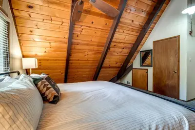 a bedroom with a large bed in a room with wooden walls at Sleek Blue Lake Springs Retreat with Deck and Yard! in Arnold