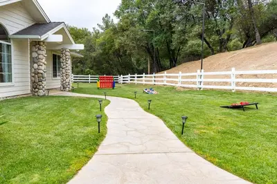 a driveway leading to a yard with a white fence at Yosemite and Bass lake I Hot tub I Game room I Sleeps 13 in Oakhurst