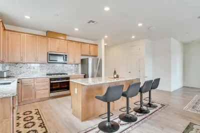 a kitchen with wooden cabinets and a island with bar stools at Newly Built Home with Patio 4 Mi to Dtwn Hollister in Hollister