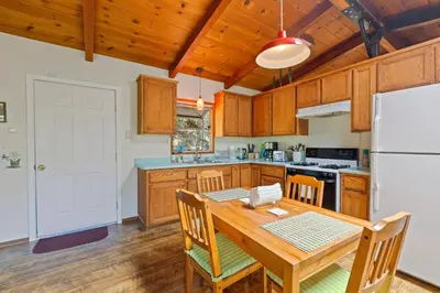 a kitchen with a wooden table and a white refrigerator at Red Cabin in Twain Harte - King bed in Twain Harte