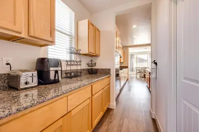 a kitchen with wooden cabinets and a counter top at 1 Mi to Golf! Spacious and Modern Home in Dinuba in Dinuba