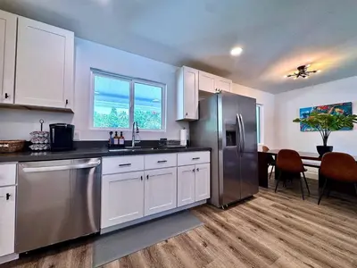 a kitchen with white cabinets and a stainless steel refrigerator at Pool Remodeled 4 Bedroom Carmichael Home in Carmichael