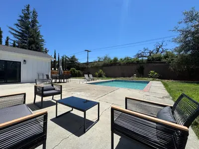 a group of benches sitting next to a swimming pool at Pool Remodeled 4 Bedroom Carmichael Home in Carmichael