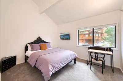 a bedroom with a bed and a desk and a window at River Run # 15 by Tahoe Getaways - 2 BR w Private Balcony, River Views & Shuttle in Alpine Meadows