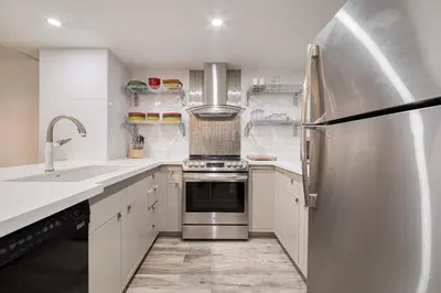 a kitchen with white cabinets and a stainless steel refrigerator at River Run # 15 by Tahoe Getaways - 2 BR w Private Balcony, River Views & Shuttle in Alpine Meadows