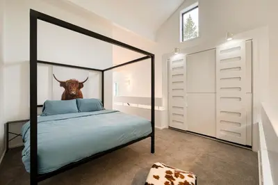 a bedroom with a four poster bed with a deer head on the wall at River Run # 15 by Tahoe Getaways - 2 BR w Private Balcony, River Views & Shuttle in Alpine Meadows
