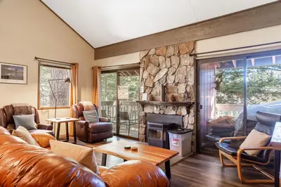 a living room with leather furniture and a stone fireplace at Walk to Village, 1+L/2BA; Jacuzzi, Parking, W/D in Mammoth Lakes