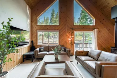 a living room with couches and a table and windows at Hearthlight Cabin at Tahoe Donner by Tahoe Getaways - Pet-Friendly 3BR w Guest Suite in Truckee