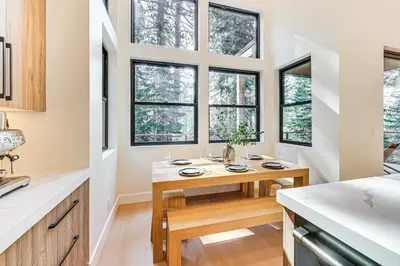 a kitchen with a wooden table and windows at 4 Mi to Soda Springs Resort Hot Tub Hideaway! in Soda Springs