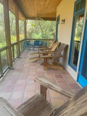 a porch with wooden benches and tables on it at Heidi's Artistic Abode in Three Rivers