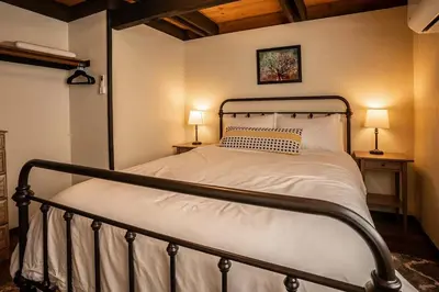 a bed in a bedroom with two lamps on two tables at Woodland Chalet Retreat with Hot Tub in Arnold