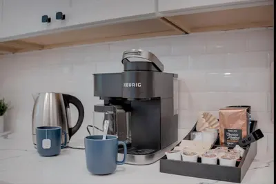 a coffee maker and cups on a kitchen counter at Folsom Old Town Escape • Cozy Cottage + Library in Folsom