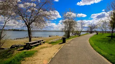 a path through a park with benches and a lake at Folsom Old Town Escape • Cozy Cottage + Library in Folsom
