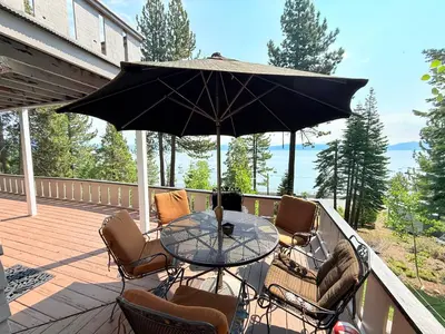 a patio table with chairs and an umbrella on a deck at Lake Tahoe Cabin I Hammocks, Paddle Boards and Bikes in Homewood