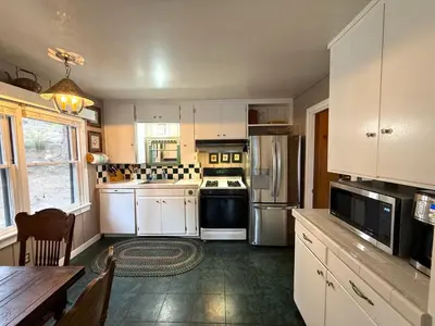a kitchen with white cabinets and a table and a refrigerator at Lake Tahoe Cabin I Hammocks, Paddle Boards and Bikes in Homewood