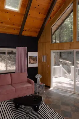 a living room with a couch and a large window at A-Frame Cabin - Sauna, Hot Tub, Fire Pit, Projector in Arnold