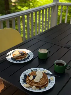 a table with two plates of pancakes and a cup of coffee at A-Frame Cabin - Sauna, Hot Tub, Fire Pit, Projector in Arnold