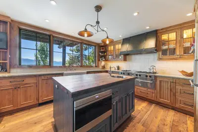 a large kitchen with wooden cabinets and a large island at Beyond the Blue Lakefront Escape by Tahoe Getaways - Pet-Friendly 6BR with Pier, Buoy & Hot Tub in Carnelian Bay
