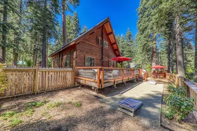 a cabin in the woods with a wooden fence at Classic Cabin in the Pines by Tahoe Getaways - Walk to Lake, Pet-Friendly 3 BR w Yard & Hot Tub! in Homewood
