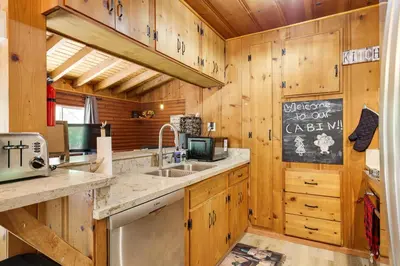 a kitchen with wooden cabinets and a sink and a refrigerator at Community Lake Access Peaceful Cabin in Sonora! in Sonora