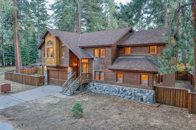 a log cabin in the woods with a fence at Tahoe Island Retreat Hot Tub & Game Room in South Lake Tahoe