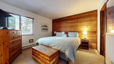 a bedroom with a bed and a wooden wall at Mammoth Sierra Townhomes #25 condo in Mammoth Lakes