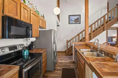 a kitchen with stainless steel appliances and wooden cabinets at Corner 3BD with Loft! Walk to Canyon and The Village! in Mammoth Lakes