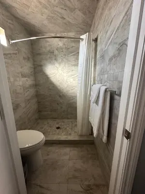 a bathroom with a white toilet and a shower at HomeTown Inn in Los Banos