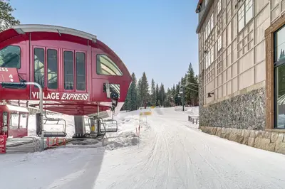 a red tram is parked next to a building in the snow at Northstar Ski-InandOut Condo with Resort Amenities! in Truckee