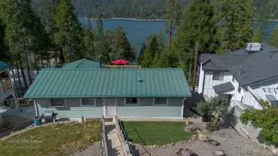 a white house with a green roof and a yard at Lake View Suite for 2-Hot Tub-Dog Friendly in Bass Lake Annex