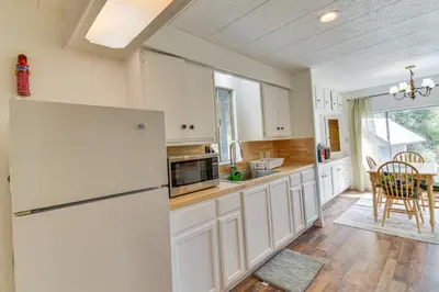 a white kitchen with a refrigerator and a table at Mtn-View Coulter Escape with Rustic Tree Lookout in Coulterville