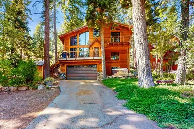 a wooden house with a garage in the woods at Tahoe Timber Retreat in Carnelian Bay