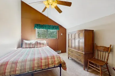 a bedroom with a bed and a ceiling fan and a chair at Dogwood Hollow in Shaver Lake