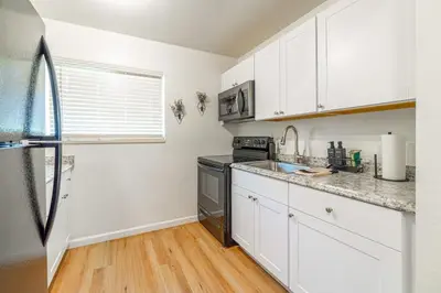 a kitchen with white cabinets and a black refrigerator at Designer Living Pet-Friendly UNR 2BR 1BA in Reno